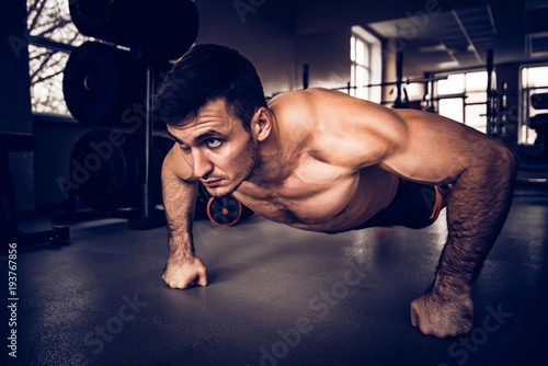 Fitness man performs push ups with naked torso