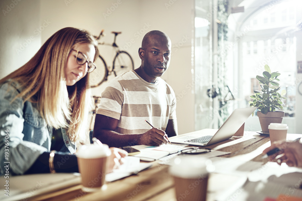 Two diverse colleagues working together at an office table Two diverse colleagues working together at an office table