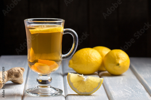 A cup of ginger tea with lemon on a wooden background.