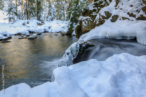 Waterfall in winter. Mountain river and snow on the mountain slopes