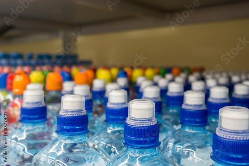 Plastic bottles with mineral water. Closeup on water bottles in raw and lines. Plastic bottles, colorful caps. Plastic bottles with water, lids.