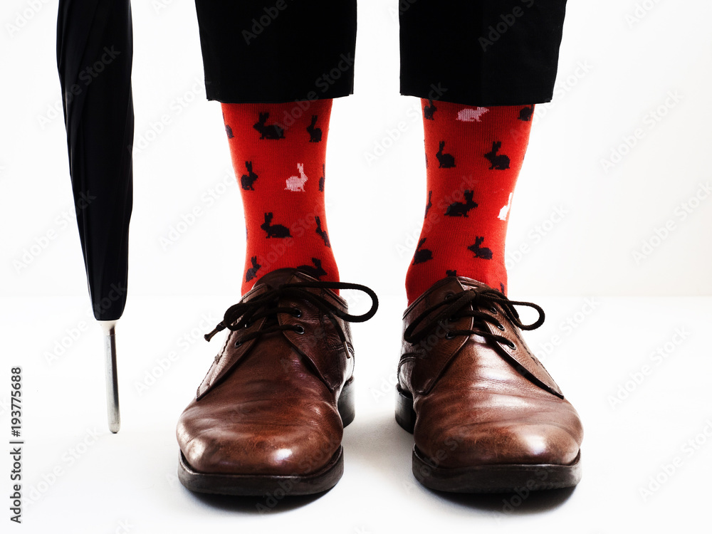 Men's legs in bright, funny socks and stylish shoes near the umbrella