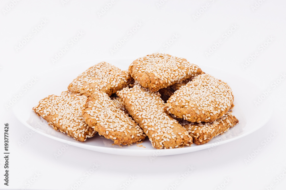 On a white plate, on a white background fresh biscuits to sesame.