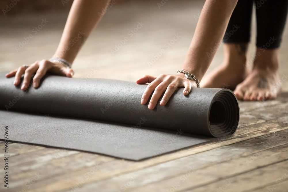 Hands of attractive young woman unfolding black yoga or fitness mat before working out at home in living room or in yoga studio. Healthy habits and lifestyle, weight loss concepts. Close up view photo - obrazy, fototapety, plakaty 