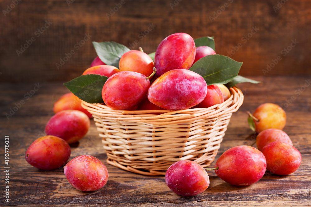 fresh plums with leaves in a basket fresh plums with leaves in a basket