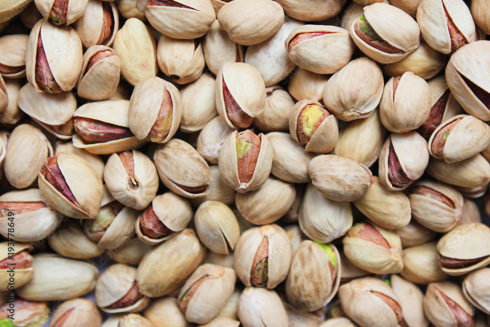 Pistachio Nuts Roasted and Salted in Shell Texture Background. Pile of Fresh Green Tasty Pistachios Top View. Healthy Organic Nutritious Nuts, Close Up View of Vegetarian and Vegan Food on the Table.