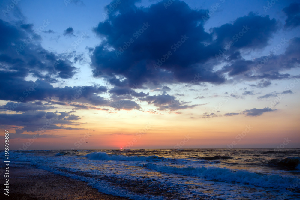 Sunset on a beach. Stormy sea, cloudy sky.