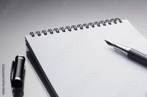 White notebook on it black pen closeup on a glossy desk, concept