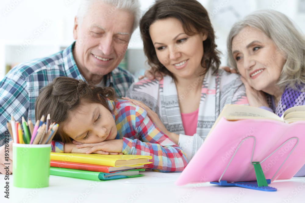 Tired little girl sleeping after doing homework while mother and Tired little girl sleeping after doing homework while mother and