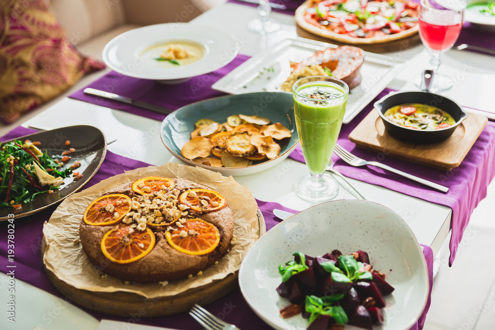 Table with vegetarian dishes - pizza, salads, pie and drinks. Food in restaurant Table with vegetarian dishes - pizza, salads, pie and drinks. Food in restaurant