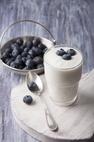 Yogurt with fresh blueberries in a glass on a white cutting board