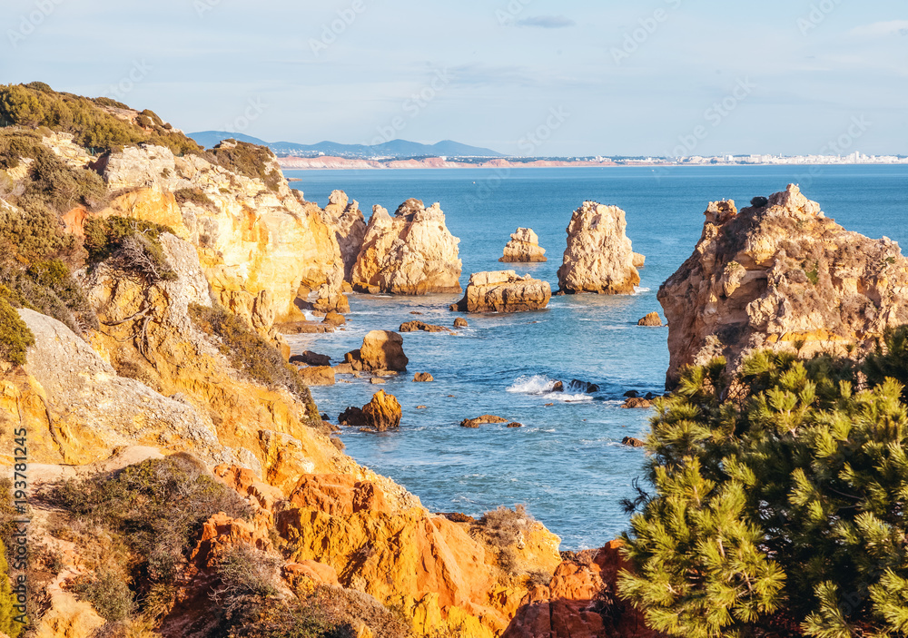 Beautiful rocky coast of the ocean, stunning beautiful landscape of the Algarve, Portugal, waves crash against the shore in splashes, travel to Europe