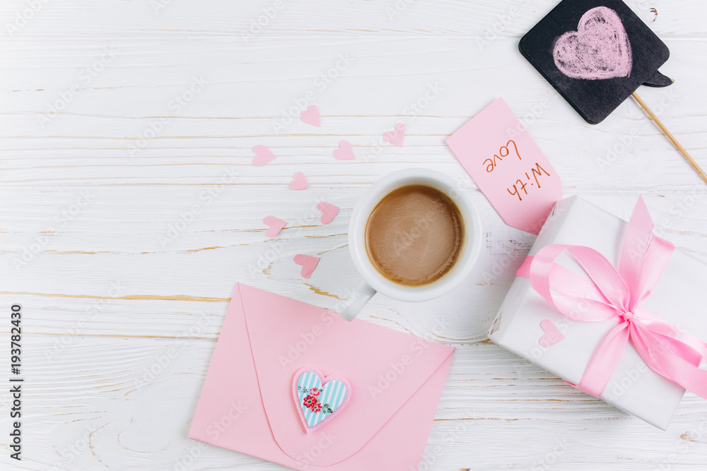 Envelope, gift, cup of coffee and paper hearts on white wooden background, copy space and flat lay. Valentines Day and Mother's Day concept. Envelope, gift, cup of coffee and paper hearts on white wooden background, copy space and flat lay. Valentines Day and Mother's Day concept.