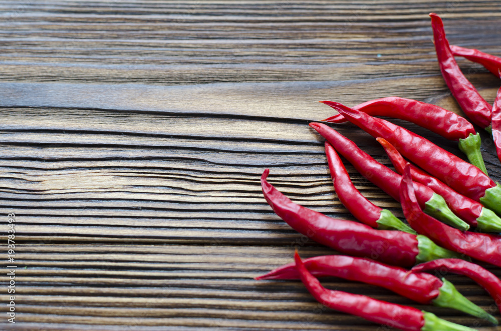group of chili peppers on brown wooden background group of chili peppers on brown wooden background