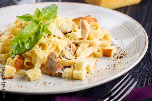 Delicious creamy italian pasta with mushrooms, parmesan cheese, basil and creamy sauce with pepper seasoning in white plate, close up