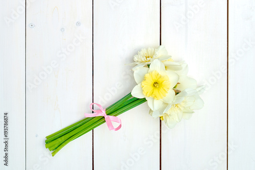 Fototapeta Naklejka Na Ścianę i Meble -  Bouquet of daffodil flowers on white wooden background, copy space. Top view, flat lay. White narcissus. Spring flowers. Greeting card for March 8 (Women's Day), Mother's day. Spring easter background