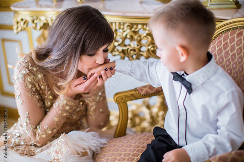 Loving mother tenderly kissing the hand his little son