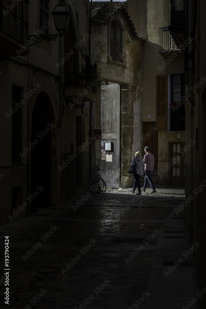 Couple in dark clear about to enter church. Dark medieval alley in Palma de Mallorca