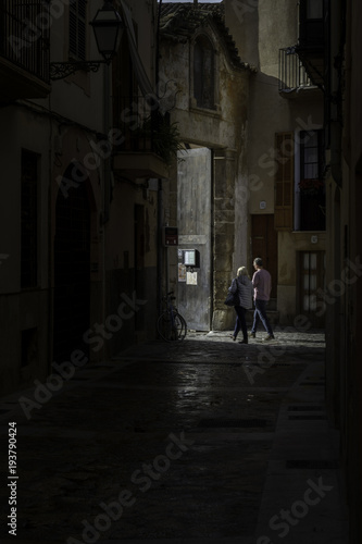 Couple in dark clear about to enter church. Dark medieval alley in Palma de Mallorca © Roberto