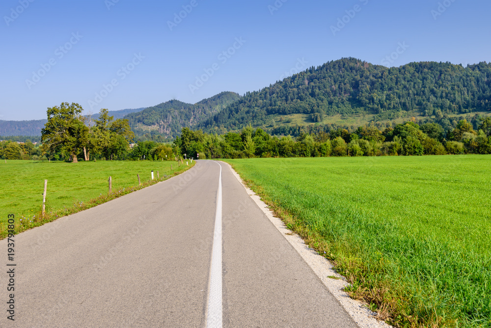 Pictorial field and an asphalt road on the background of mountain peaks, Bled, Slovenia. Pictorial field and an asphalt road on the background of mountain peaks, Bled, Slovenia.