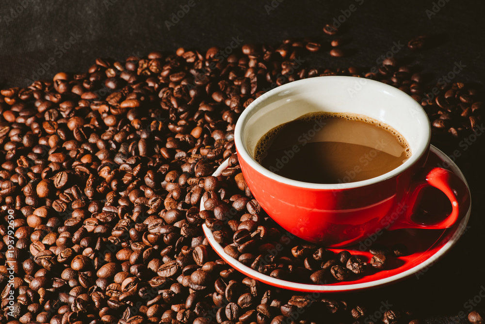 coffee in red cup and coffee beans are the background. coffee in red cup and coffee beans are the background.