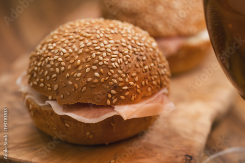 prosciutto and cream cheese in a sesame buns with beer on wood board