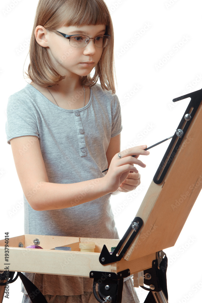 Girl teenager painting on an easel isolated on white background. Blonde girl with glasses Girl teenager painting on an easel isolated on white background. Blonde girl with glasses