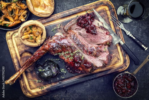 Marinated sliced barbecue aged leg of venison with chanterelles and Yorkshire pudding as top view on a rustic board