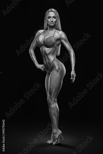 Black and white full size photo of fitness bikini model Confident attractive young female bodybuilder posing slim body perfect shape Muscular abs legs booty arms chest Sporty women on black background