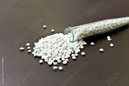 Plastic pellets. White Colorant for plastics, in test-tube against a dark background. Plastic Raw material .