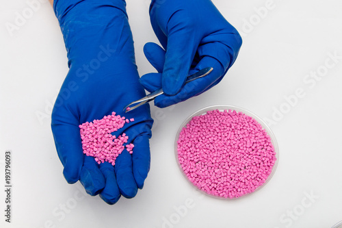 Plastic pellets . Colorant for polymers in granules. Plastic pellets in the hands with gloves and tweezers photo