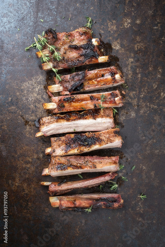 Barbecue spare ribs St Louis cut with hot honey chili marinade sliced as top view on an old rustic board