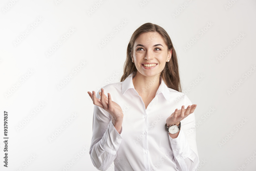 Portrait of happy young businesswoman wearing white shirt while standing with her arms rasied and wondering. Isolated on white background. Portrait of happy young businesswoman wearing white shirt while standing with her arms rasied and wondering. Isolated on white background.