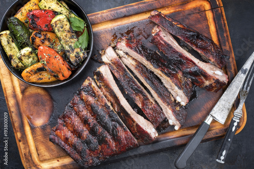 Barbecue spare ribs St Louis cut with hot honey chili marinade sliced as top view on an old rustic board