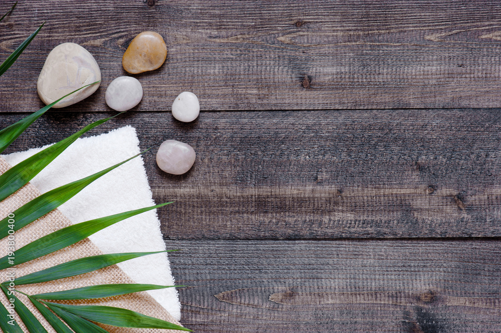Brown wooden background with terry towel, palm leaf and stones Brown wooden background with terry towel, palm leaf and stones