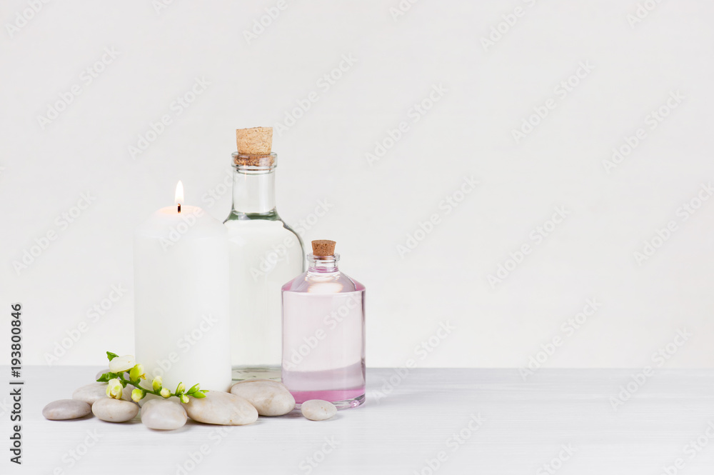 Spa light composition with burning candle, glass bottles and stones