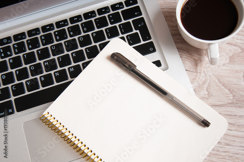 Notepad, laptop and coffee cup on wood table
