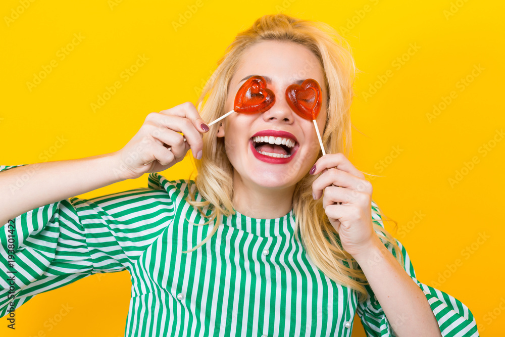 Cheerful blonde woman hold heart-shaped lollipops Cheerful blonde woman hold heart-shaped lollipops