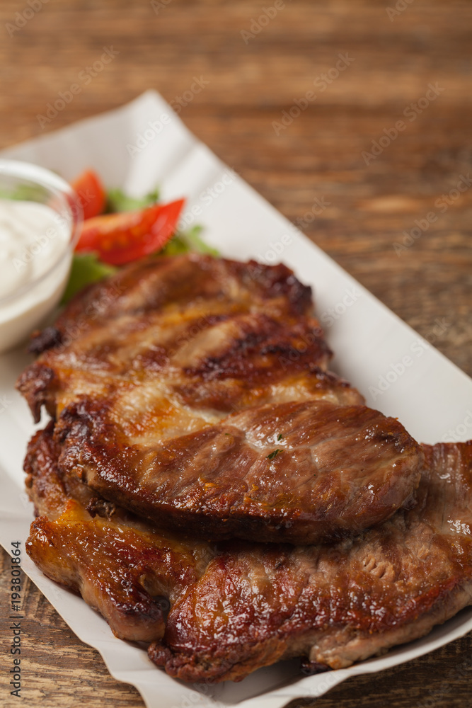 Grilled pork neck served on paper trays. Grilled pork neck served on paper trays.