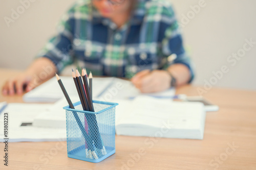 close up black pencil with asian woman reading textbook and doing homework or research project in library room ,education concept