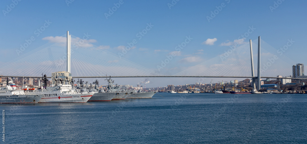 View on Golden Horn Bay (or Zolotoy Rog) with Golden Bridge (or Zolotoy bridge) and parking of military battleships of Russian Pacific Navy with few battle ships (cruisers). Russia, Vladivostok.