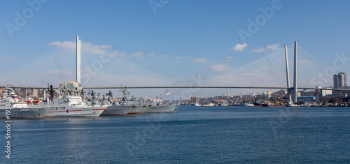 View on Golden Horn Bay (or Zolotoy Rog) with Golden Bridge (or Zolotoy bridge) and parking of military battleships of Russian Pacific Navy with few battle ships (cruisers). Russia, Vladivostok. © Денис Кабелев