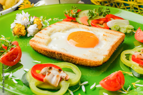 Egg in toast bread baked in the shape of a flower with fresh vegetables and yogurt