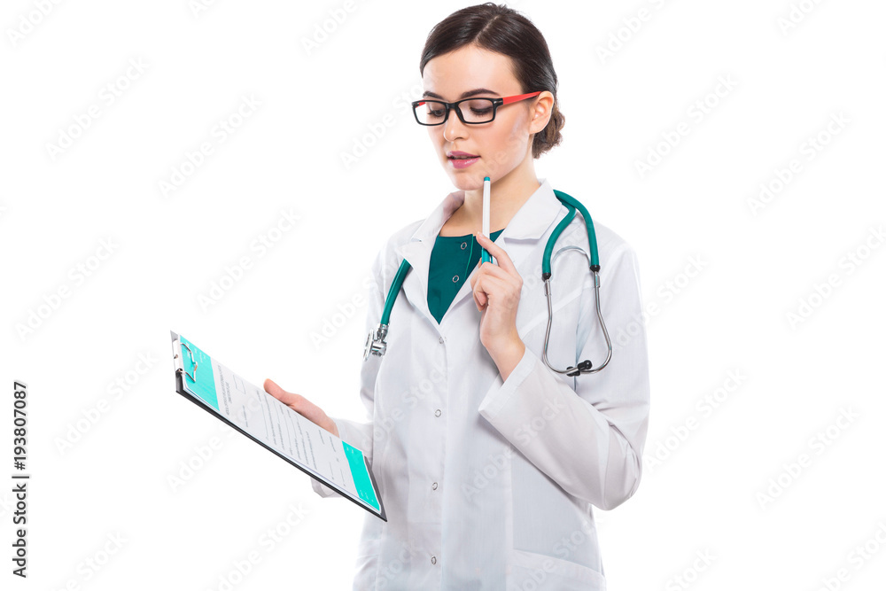 Young woman doctor with stethoscope holding clipboard and pen in her hands in white uniform on white background Young woman doctor with stethoscope holding clipboard and pen in her hands in white uniform on white background