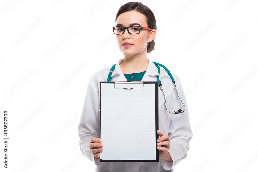 Young woman doctor with stethoscope holding and showing clipboard in her hands in white uniform on white background