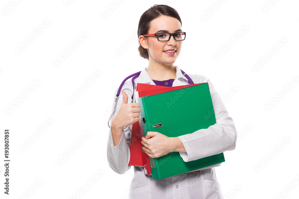 Young woman doctor with stethoscope holding binders in her hands with thumb up in white uniform on white background Young woman doctor with stethoscope holding binders in her hands with thumb up in white uniform on white background