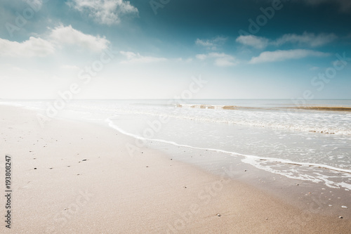 Sandy beach and blue sky with clouds. Coast of the North sea in the Netherlands