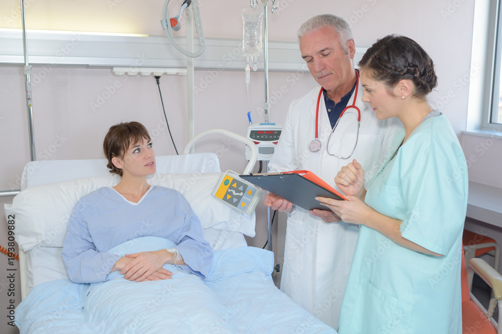 Doctor and nurse talking to patient in hospital bed Doctor and nurse talking to patient in hospital bed