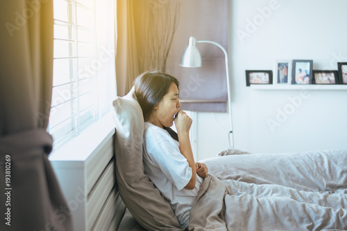 Young asian female coughing and sitting on her bed,Concept of health