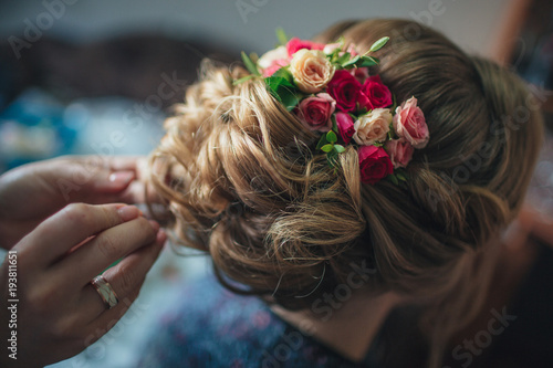Fashionable wedding hairstyle with fresh roses. Beautiful styling, rear view. The bride stands with his back to the camera.